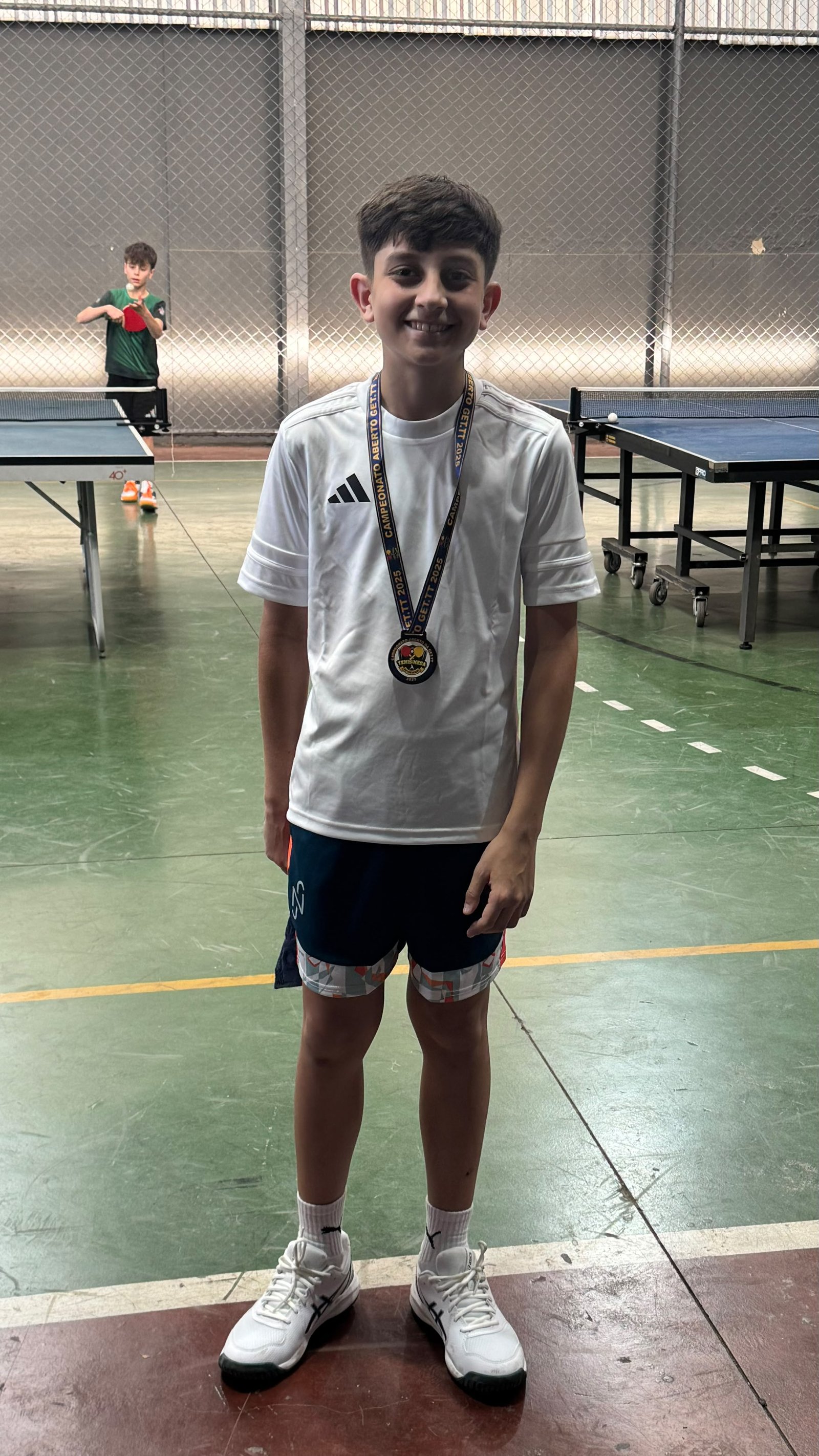 Rafael com sua medalha em uma quadra de tênis de mesa